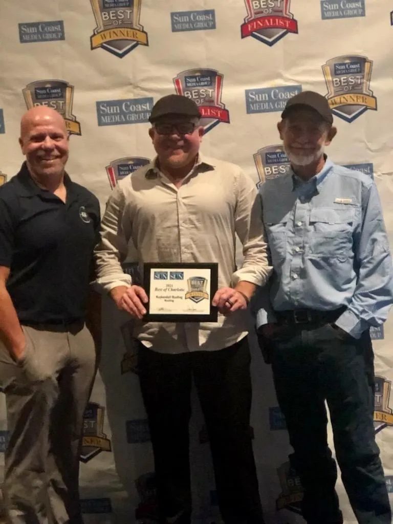 Three members of Kuykendall Roofing standing in front of a Sun Coast Best of the Best backdrop, with one holding a framed award for roofing excellence