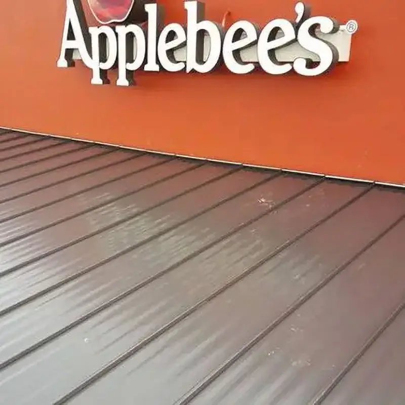 Close-up of a metal commercial roof under Applebee’s signage, showing Kuykendall Roofing’s work with flat and sloped retail building roofs