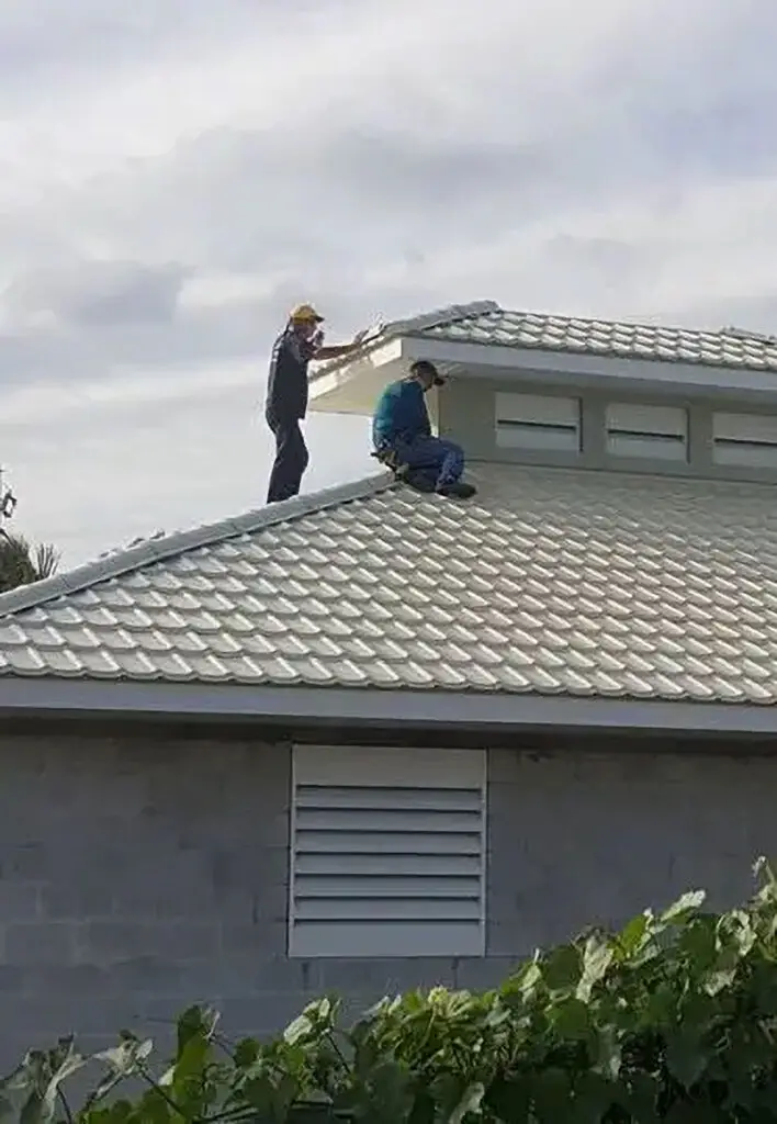 Two Kuykendall Roofing inspectors walking on a gray tile roof during a structural roof inspection to assess storm damage and material condition