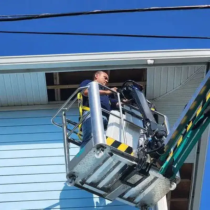 Close-up of Kuykendall Roofing expert working on soffit and fascia installation from a mechanical lift, highlighting precision workmanship