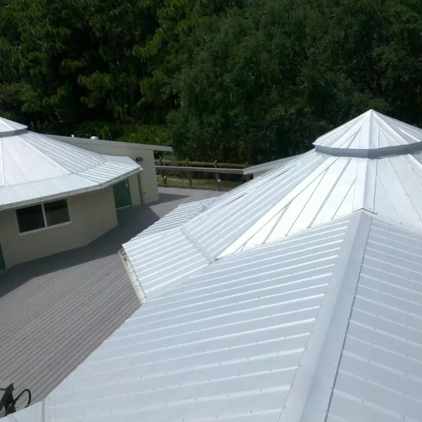 New white metal roof with a multi-angled structure surrounded by trees, representing high-quality roofing craftsmanship by Kuykendall Roofing, shown alongside FAQ about services