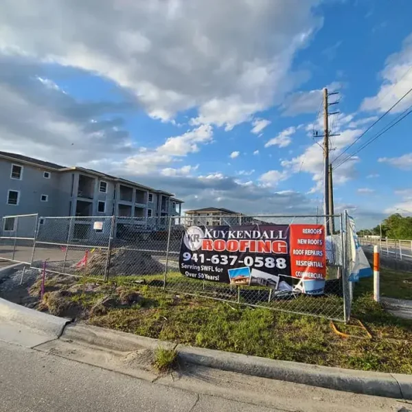 Commercial-Roofing Kuykendall Roofing banner displayed at a commercial construction site, promoting roofing replacement services for new business properties