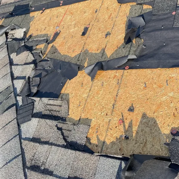 Shingles torn off a residential roof exposing plywood decking, an example of visible storm damage assessed by Kuykendall Roofing after severe weather