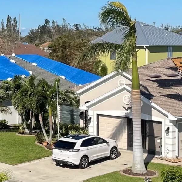 Hurricane Tarps Multiple Florida homes with blue tarps over storm-damaged roofs, temporarily protected by Kuykendall Roofing’s emergency roof repair services