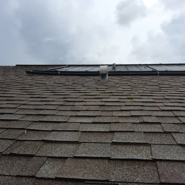 View of a sloped asphalt shingle roof under cloudy skies, representing the importance of regular roof inspections in Florida’s storm-prone climate